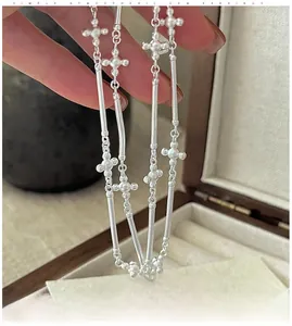 Détail du collier croix en argent S925 mat avec de longs maillons texturés au style vintage