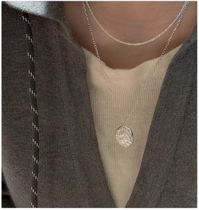Detail of S925 sterling silver layered necklace with irregular round embossed pendant