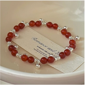 Detail of red agate bead bracelet with silver bell charms and romantic card display