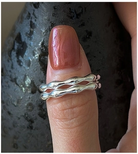 Close-up of a S925 sterling silver wavy textured double ring on model's thumb