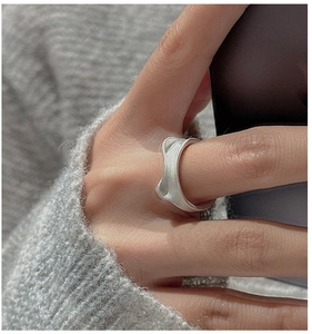 Macro view of matte silver cat ear ring with irregular organic wave design on finger