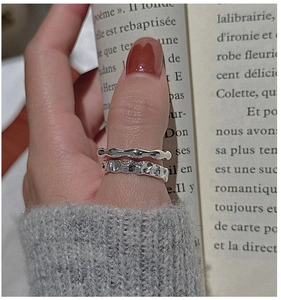 Detail of S925 sterling silver wavy and hammered texture rings on thumb
