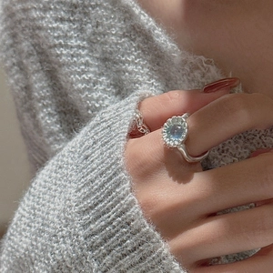 Anello margherita in argento S925 con gemma blu su modella che indossa un maglione a maglia