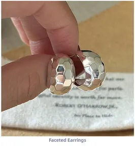 Detailed macro view of silver hammered hoop earrings held by hand for texture