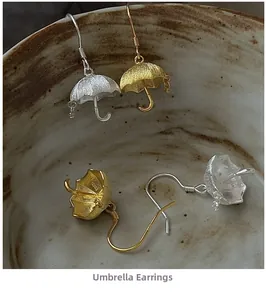 Close-up of S925 sterling silver umbrella earrings in gold and matte silver finishes