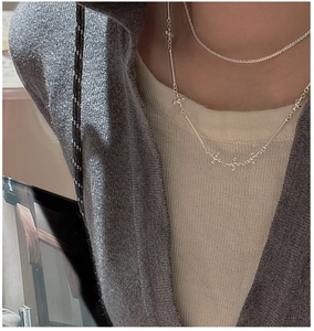 Gros plan du collier double rang croix en argent avec chaîne tennis pavée et détails barres