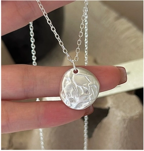 Detail of silver textured round pendant necklace with two sparkling cubic zirconia stones
