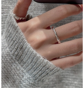 Close-up of S925 sterling silver wavy and lava textured rings on a grey knit sweater