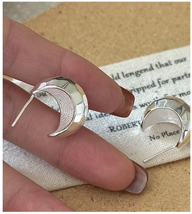 Macro shot of S925 sterling silver crescent earrings with faceted geometric CNC cut texture