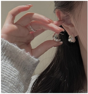 Detail shot of hammered silver hoop earrings and minimalist ring with metallic texture