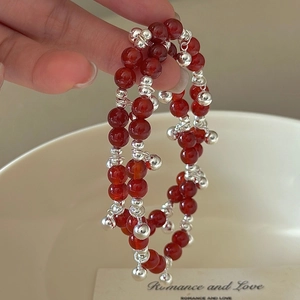 Double-layered red agate bead bracelet with silver bells on a minimalist vintage style