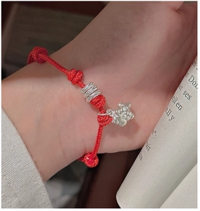 Close-up of red woven bracelet featuring S925 silver bear and bead charms on wrist