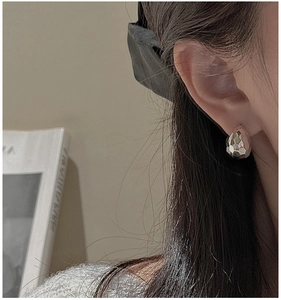 Macro shot of silver teardrop earrings with hammered texture on a model side profile