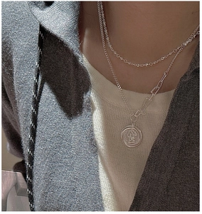 Detail of layered S925 sterling silver necklaces with coin pendant on a model