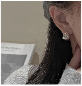 Macro view of sterling silver stud earrings featuring a hammered geometric faceted finish