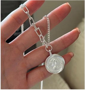 Macro detail of silver S925 necklace featuring U-link chain and queen portrait medal