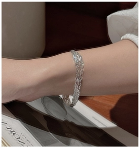 Detailed macro view of S925 sterling silver woven multi-strand bracelet on wrist
