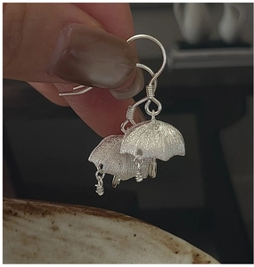 Detailed macro view of S925 sterling silver umbrella drop earrings with brushed metal texture