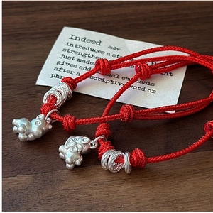 Detail view of S925 silver bear charms on adjustable red braided cord bracelets