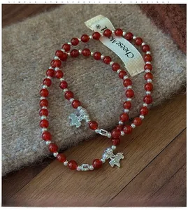 Gros plan d'un bracelet en argent S925 avec perles d'agate rouge et breloques poney