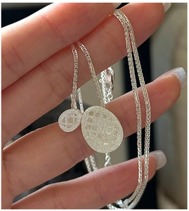 Macro detail of S925 sterling silver oval pendant with brushed mesh texture on woven chain