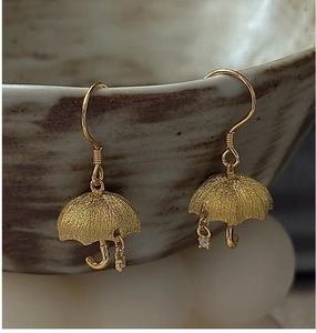 Detail of golden umbrella earrings with matte finish and tiny crystal drops