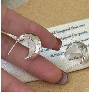 Detailed macro view of S925 sterling silver crescent earrings with hammered geometric facets