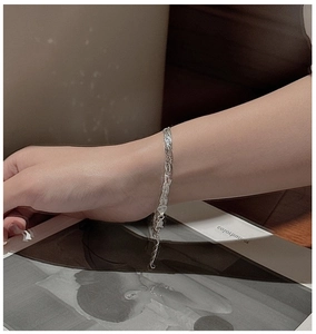 Detail of woven S925 silver bracelet with heart charm and lobster clasp on wrist