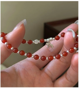 Détail du bracelet en agate rouge avec pendentif cheval et perles de pièces en argent