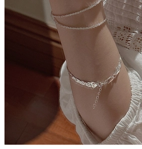Detailed shot of layered S925 silver woven bracelet and heart pendant on a wrist