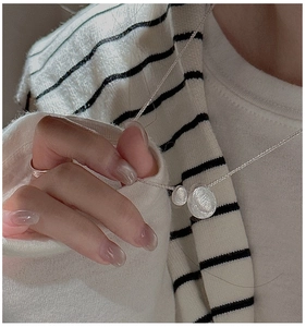 Close-up of S925 silver necklace featuring hammered texture bean pendants on model