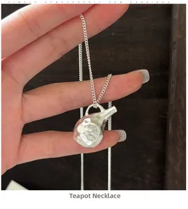 Macro detail of silver kettle pendant with textured hammered finish and fine link chain
