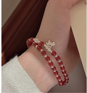 Détail d'un bracelet double en agate rouge avec breloque cochon en argent sterling au poignet