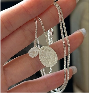 Macro detail of S925 sterling silver necklace with textured oval pendant and woven chain