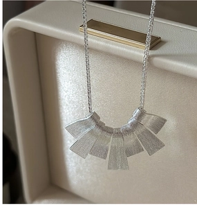 Macro shot of S925 sterling silver necklace featuring brushed metal texture fan pendants