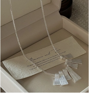 Macro detail of brushed texture silver pendant necklace on cream velvet jewelry box