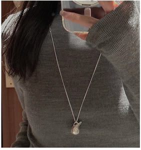 Detail of S925 silver long necklace with hammered texture pendant on a grey sweater