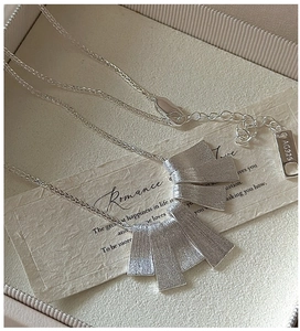 Macro shot of S925 sterling silver tag and brushed texture pendant on a fine chain