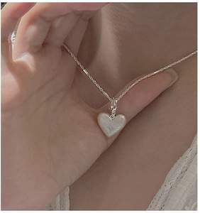 Close-up of a brushed S925 sterling silver heart pendant with a star engraving on a necklace