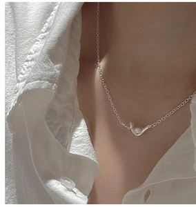Detail of S925 sterling silver knotted wavy necklace with zircon heart pendant on neck