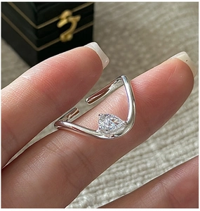 Macro detail of S925 silver wavy ring featuring a pear-shaped zircon on a finger
