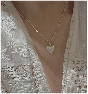 Close-up of S925 sterling silver heart pendant with star motif on a female model