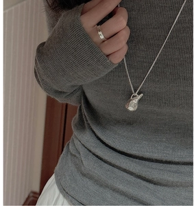 Macro view of S925 silver necklace with hammered texture pendant on knit sweater
