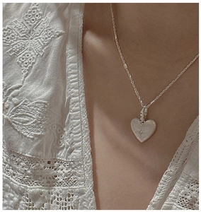 Close-up of S925 sterling silver heart pendant with brushed texture and star engraving