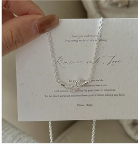 Close-up of S925 silver knot necklace with a heart-shaped zircon on a gift card