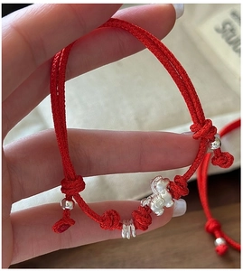 Detail of red braided rope bracelet with silver pig charm and adjustable knot closure