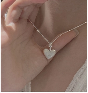 Detail of S925 sterling silver heart pendant with star engraving and textured finish