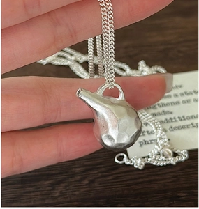 Macro shot of S925 silver kettle pendant with hammered texture and fine metal chain
