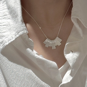 S925 sterling silver necklace with textured fan-shaped pendants on model in white shirt
