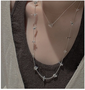 Detail of layered S925 silver necklaces with 3D animal charms on a knit sweater